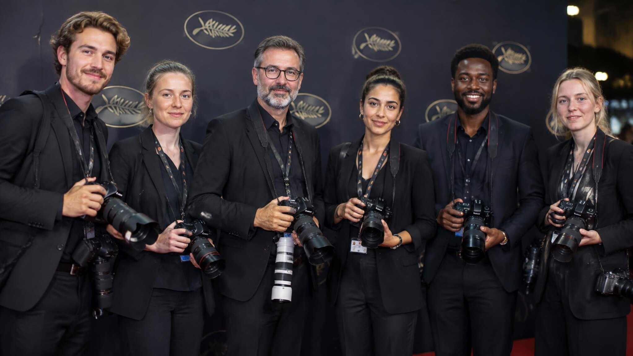Photographers lined up in front of a media wall at a premiere